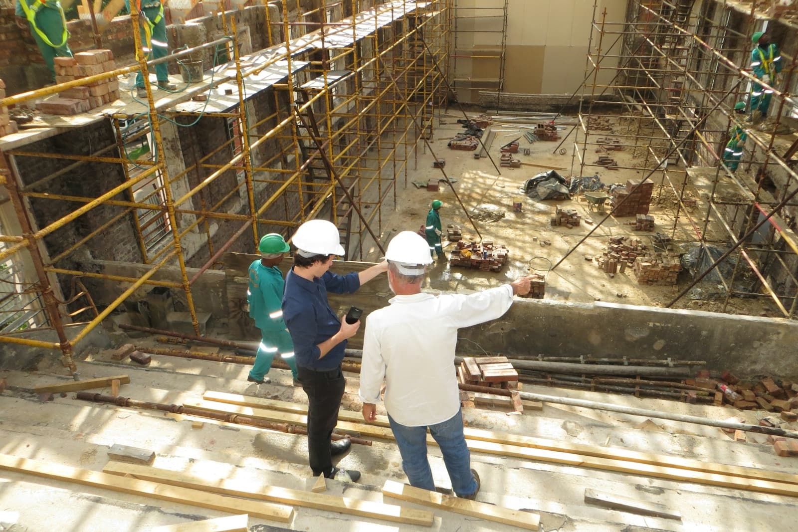 Construction crew in hard hats reviewing an excavated foundation area surrounded by scaffolding