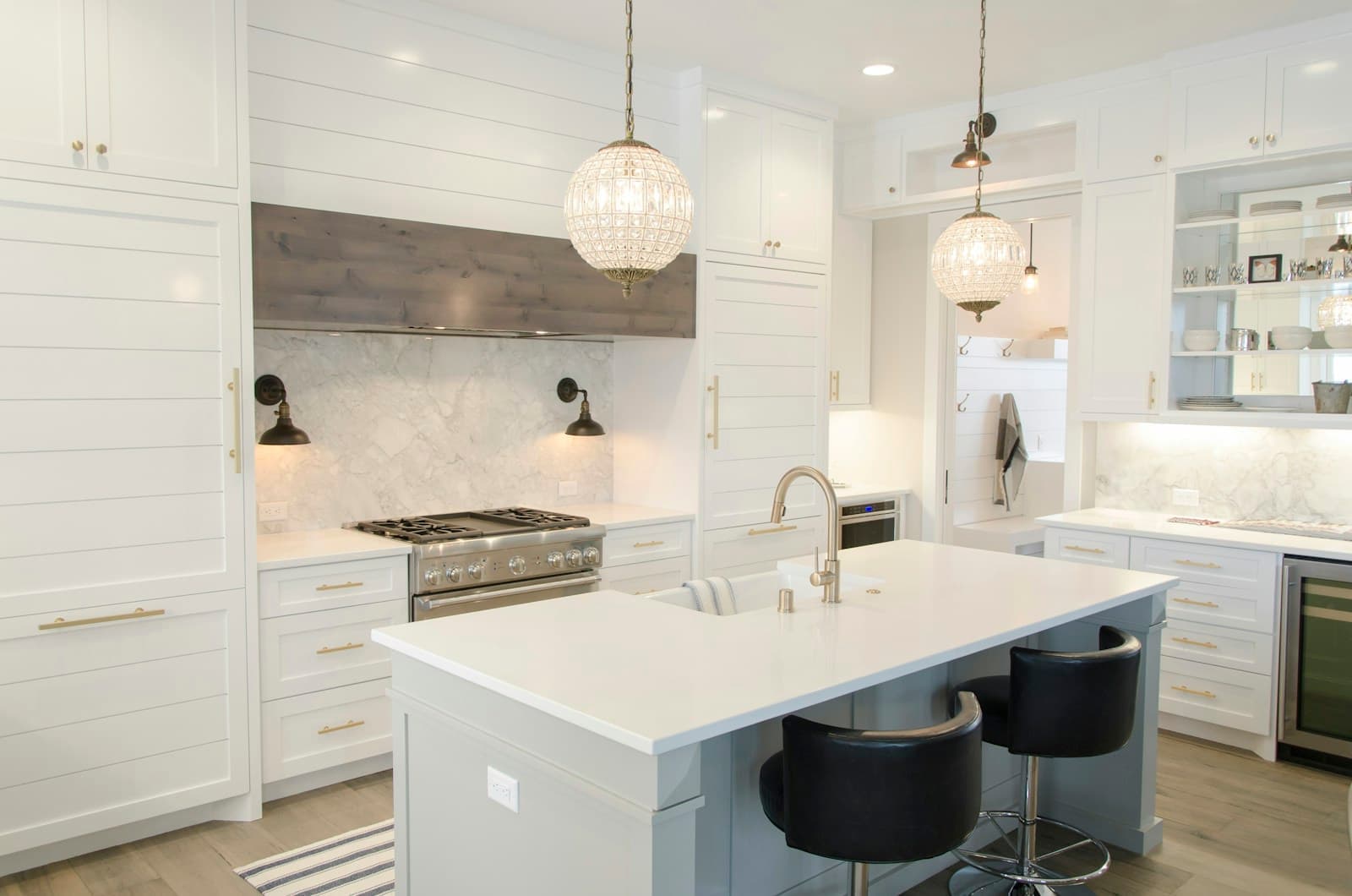 White kitchen with a large island, pendant lights, shiplap walls, and built-in shelving