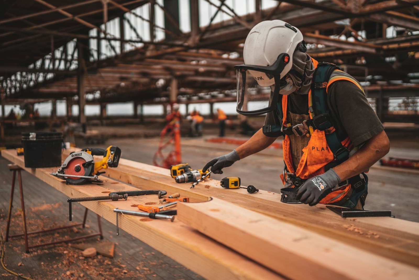 Carpenter in safety gear cutting framing lumber with a circular saw on a job site